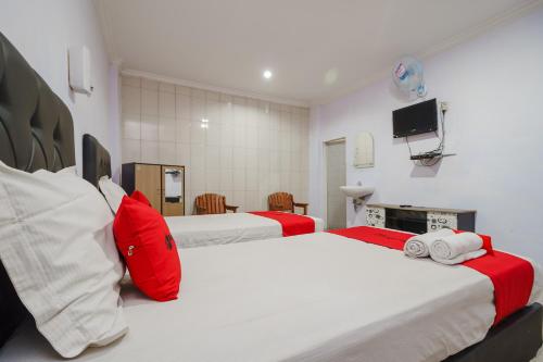 巴拉巴特RedDoorz near Danau Toba Parapat的一间卧室配有两张红色和白色床单