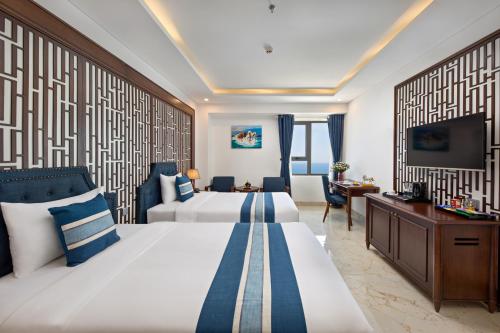 岘港Eden Ocean View Hotel Da Nang的酒店客房设有两张床和电视。
