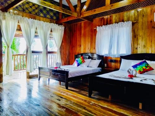 Buruanga白沙滩前别墅的配有木墙和窗户的客房内的两张床