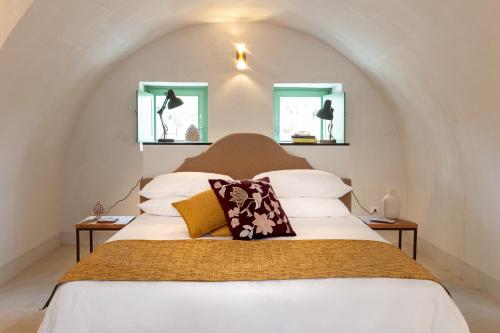 诺托Relais Terre di Romanello的卧室配有一张白色大床和两个窗户
