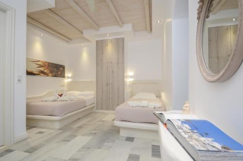 阿吉奥斯普罗科皮奥斯Ostria Hotel的白色客房的两张床,配有镜子