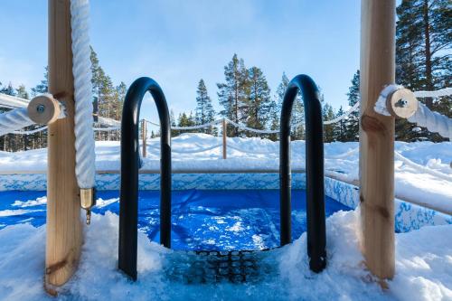 萨利色尔卡Northern Lights Village Saariselkä的雪地中的游泳池,带滑雪杆