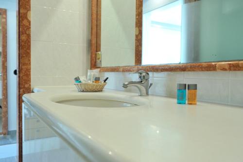 波塞蒂波塞蒂套房度假酒店的浴室水槽配有镜子和牙刷篮