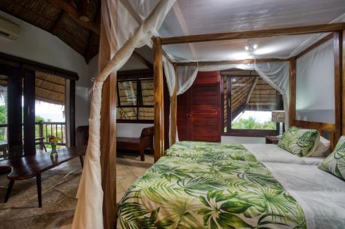 维兰库卢什帕拉伊索别墅的一间卧室配有一张天蓬床、书桌和窗户。