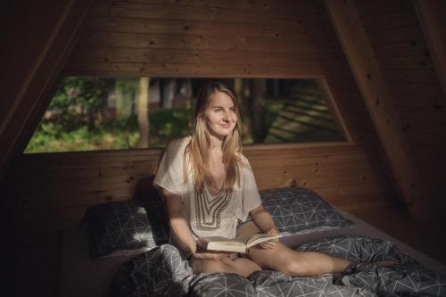 莫济列Forest Camping Mozirje的坐在床上读书的女孩