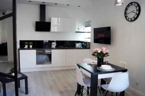 托伦Black & White Apartament的厨房配有黑桌和白色橱柜
