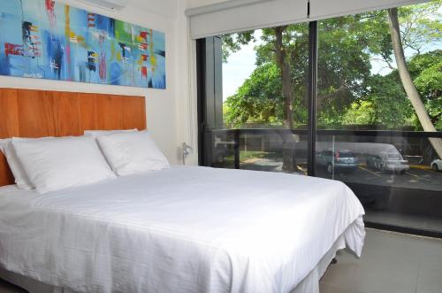 马那瓜中国人之家公寓酒店Apart-Hotel Casa de China的卧室设有白色的床和大窗户