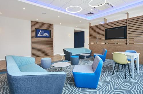 格里姆斯比格里姆斯比智选假日酒店的一间设有蓝色椅子和平面电视的等候室
