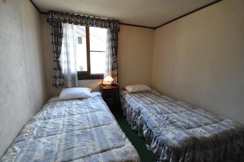 白马村风白马旅馆的带窗户的客房内的两张床