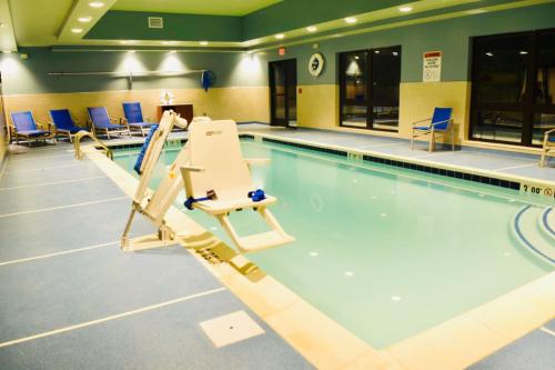 米德尔敦Holiday Inn Express & Suites - Middletown, an IHG Hotel的一个带椅子的室内游泳池和游泳池