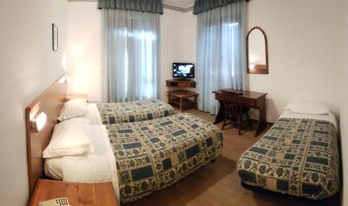 塔尔维西奥国际酒店 的一间卧室配有两张床、一张桌子和一台电视。