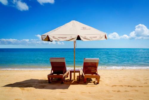 勒吉安阿斯塔基纳Spa酒店的海滩上的两把椅子和一把遮阳伞