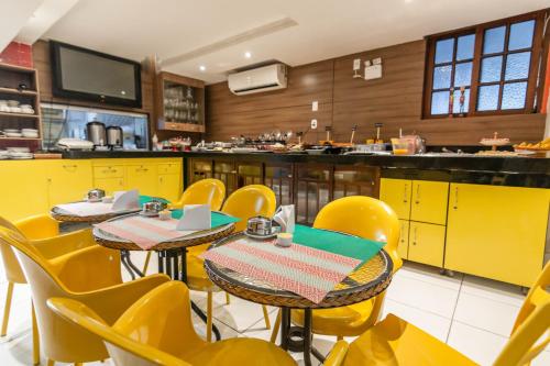 马塞约格哥达艾马酒店的一间带黄色桌椅的餐厅和一间厨房