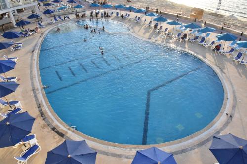 亚历山大Golden Jewel Hotel的一个带蓝伞的大型游泳池,里面的人