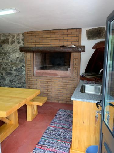 桑塔纳Casa do Ribeiro Frio的厨房设有砖砌壁炉和木桌。