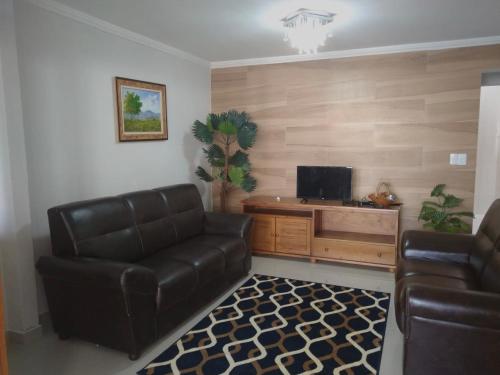 阿拉亚尔-杜卡布Bela casa的客厅配有真皮沙发和电视