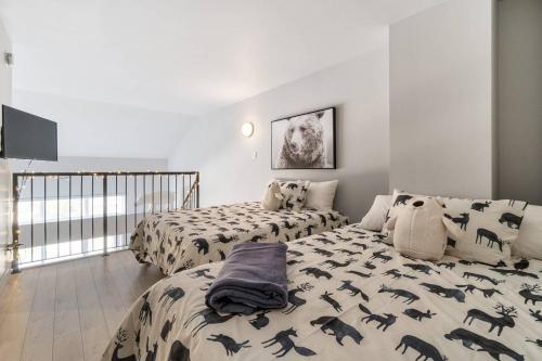博普雷INITIAL - L'OURS - Mont-Sainte-Anne的一间卧室配有两张床和黑色恐龙枕头