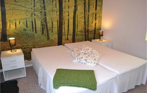 Karlstrup StrandAmazing Home In Solrd Strand With 3 Bedrooms And Sauna的一间卧室配有一张带森林绘画的床