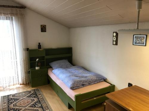 瓦尔德克赖堡Gemütliches Gästehaus!的一间卧室配有一张绿色的床和一张桌子