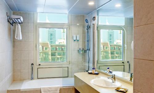 迪拜Roda Al Murooj Residences的带淋浴和盥洗盆的浴室以及窗户。