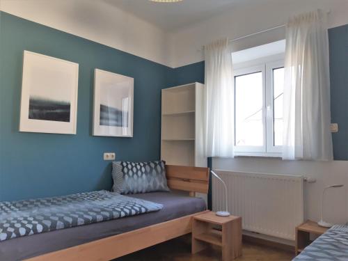 克拉根福Apartment and more的一间拥有蓝色墙壁的卧室、一张床和窗户