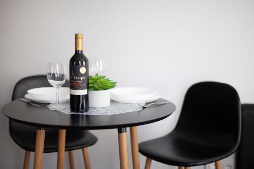 考纳斯Oak house apartments的一张黑桌,上面有一瓶葡萄酒和一杯