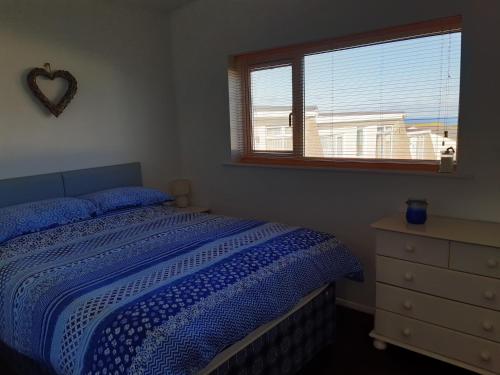 布德Chalet 18 Widemouth Bay Holiday Village的一间卧室配有床、窗户和梳妆台