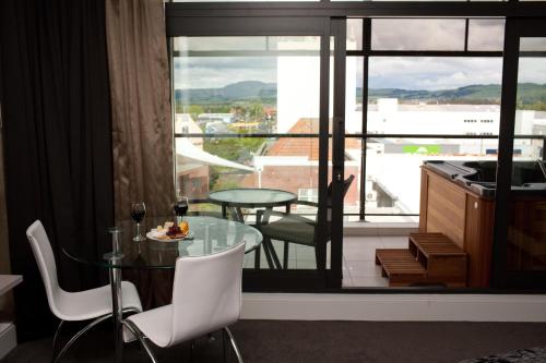 罗托鲁瓦Quest Rotorua Central的客房设有玻璃桌、椅子和阳台。