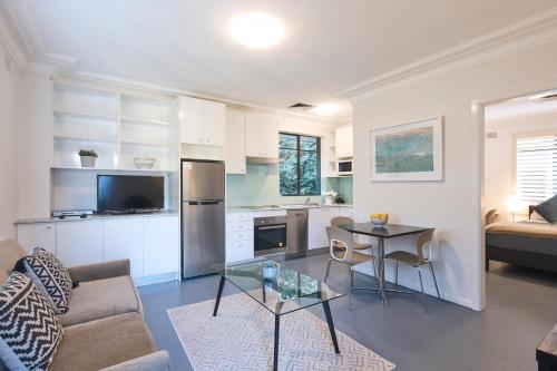 悉尼摩士曼巴兰坦大街服务式公寓式酒店的厨房以及带桌子和沙发的客厅。