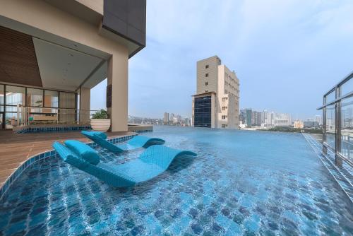 宿务Citadines Cebu City的一座带两把蓝色椅子的游泳池,位于一座建筑的顶部