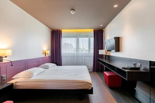 日内瓦Hôtel Les Nations的一间卧室配有一张大床和电视