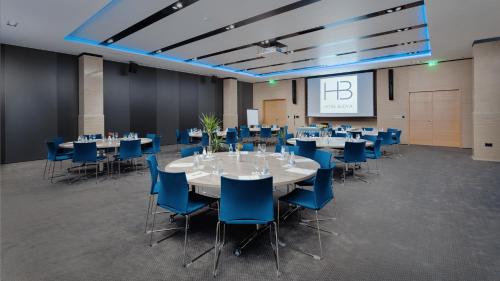 布德瓦布德瓦酒店的一间会议室,配有桌子、蓝色椅子和屏幕