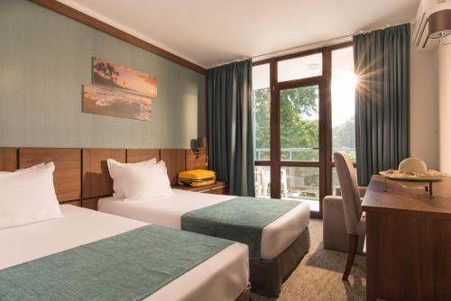 阳光海滩Hotel Pomorie Sun的酒店客房配有两张床和一张书桌