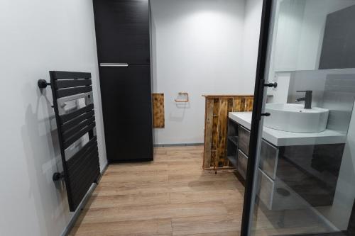 卢维耶La Dimiere - Le Postel - Appartements de standing en hyper-centre - Louviers的浴室设有白色水槽和黑色门。