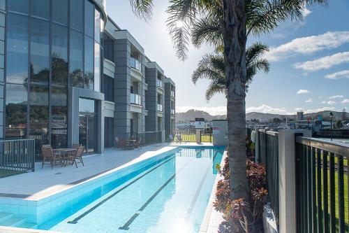 吉斯伯恩Portside Hotel Gisborne的一座棕榈树建筑的一侧的游泳池