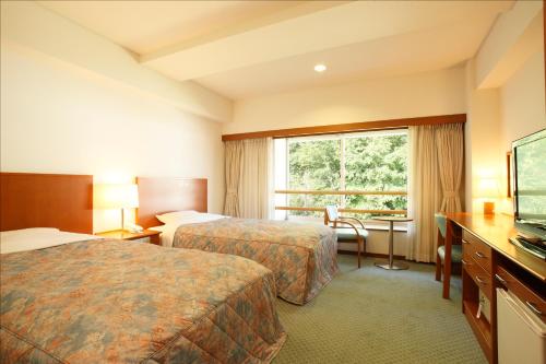 雫石町Kyukamura Iwate-Amiharionsen的酒店客房设有两张床和窗户。