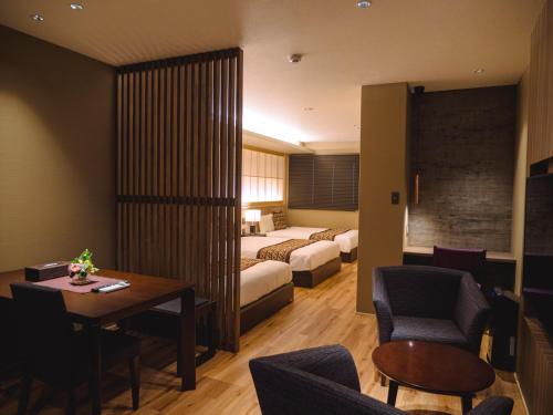 别府GRAND BASE Beppueki的酒店客房带一张床、一张桌子和椅子