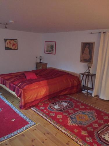 林德拉尔Schönenborn的一间卧室配有一张带红色床单和2个地毯的床。