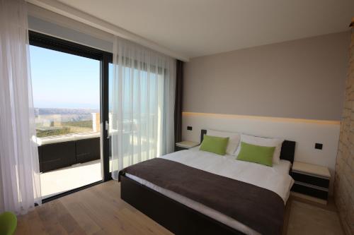 斯姆里卡Villa Infinity的一间卧室配有一张带绿色枕头的床和大窗户