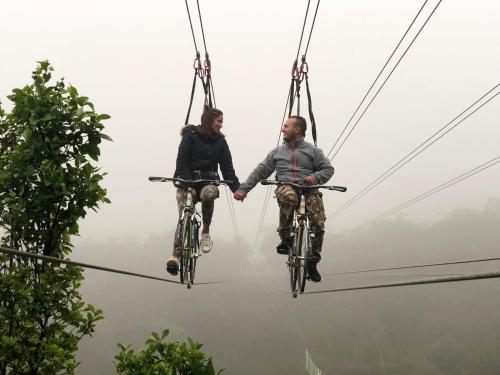 莱瓦镇Glamping y Chalet Aventura Park Villa De Leyva La Periquera的两人骑着自行车,骑着一条高空滑索