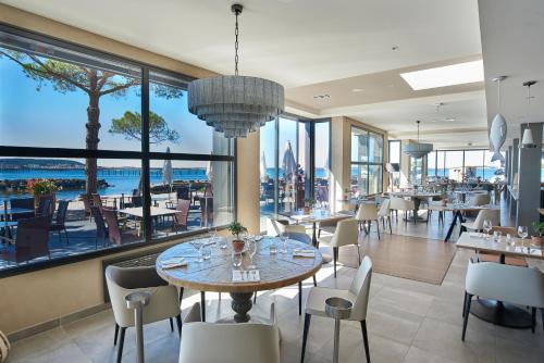 布齐盖蓝色海岸酒店的餐厅设有桌椅和大窗户。