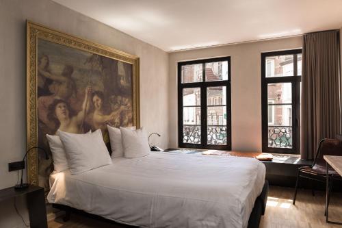 安特卫普奥卡瑟德尔酒店的卧室配有一张大床,墙上挂有绘画作品