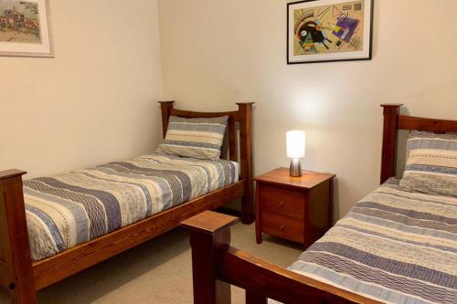 金斯科特Leeward 'tranquil beachfront'的一间卧室配有两张床和床头灯。