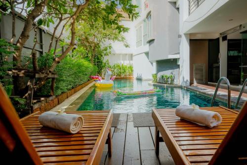 曼谷Peace Land Khaosan的一个带两张木桌和泳池浮动的游泳池