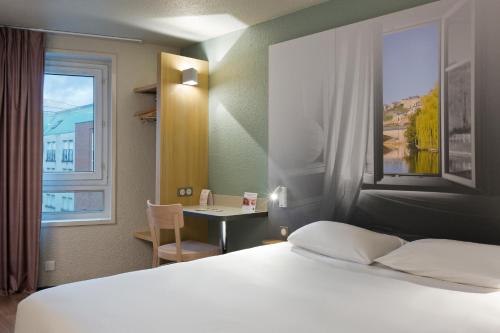 勒芒B&B HOTEL le Mans Centre的一间卧室配有一张床、一张书桌和一个窗户。