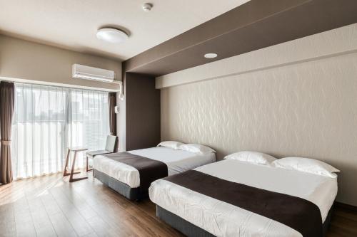 大阪斯选・新大阪酒店公寓的酒店客房设有两张床和窗户。