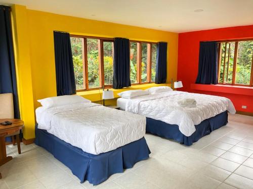 埃雷迪亚La Casa de Cariari Al Golf的红色和黄色墙壁的客房内的两张床
