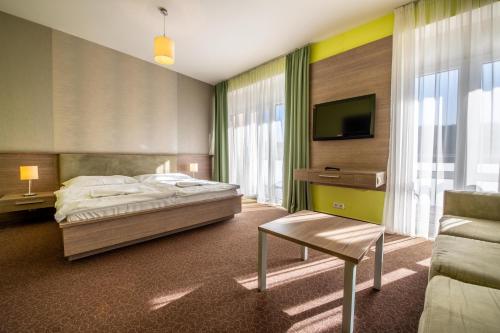 Lučivná鲁奇维纳酒店的一间卧室配有一张床、一台电视和一张沙发