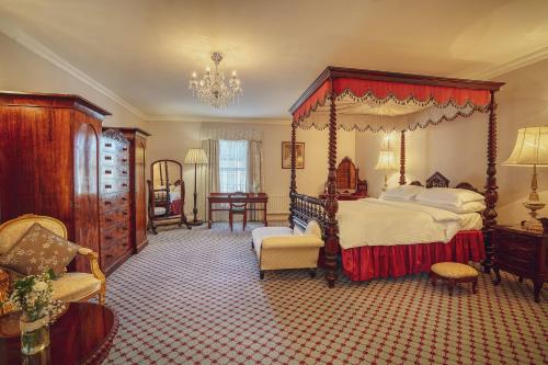 莱特肯尼城堡树林乡间酒店的一间大卧室,配有天蓬床和椅子