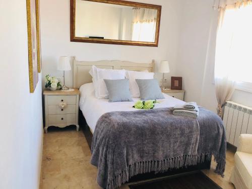 马尔格莱特德玛Apartamento con terraza y piscina en Malgrat de Mar的一间卧室配有一张带毯子和镜子的床